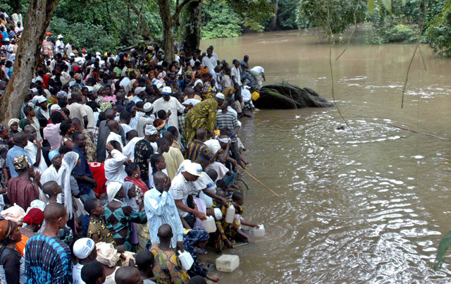 People gather at the Osun sacred river to collect water during an annual festival held to worship a river goddess in Osogbo, southwest Nigeria, August 4, 2006. The annual cultural festival around a sacred grove, enlisted as a UNESCO World Heritage Centre in 2005, draws tens of thousands of ethnic Yoruba Nigerians and others to mark the remains of a mystic bond between the people and a river goddess "Osun," believed to bring divine favour and fertility. REUTERS/Akintunde Akinleye (NIGERIA)